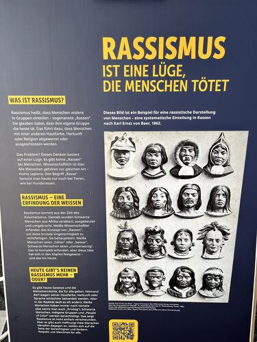 Zu sehen ist eine Infotafel mit aufklärenden Texten über Rassismus und einer historischen Abbildung