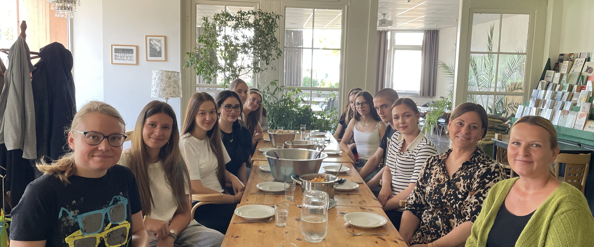 Gruppe von Menschen an einem Tisch, gedeckt für ein großes gemeinsaes Essen
